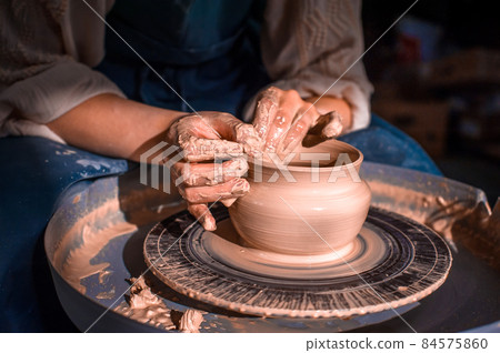 The hands of the master who makes the jug. Close-up. 84575860