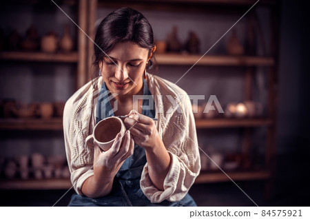 Beautiful female master making ceramic pot on the pottery wheel . Craft production. Beautiful female master making ceramic pot on the pottery wheel . Craft production. 84575921