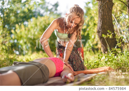 Massage professional applies her massage skills on her client in the sunlight. 84575984