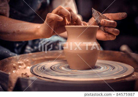 Creating a jar or vase. Master crock. Making clay jug. The sculptor in the workshop makes a jug out of earthenware closeup. Potter's wheel. Pottery concept. 84575987
