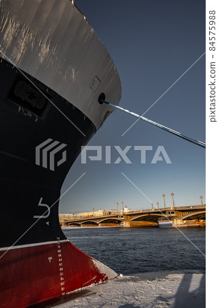 The panoramic view of the winter city Saint-Petersburg at sunny day, big ship moored near Blagoveshchensky bridge, mooring lines, thick ropes, river and bridge on background 84575988