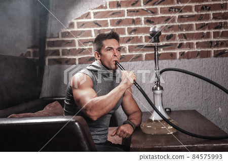 Young fellow smoking shisha in nightclub. Young fellow smoking shisha in nightclub. 84575993