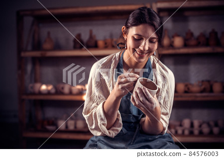 Beautiful handicraftsman molding a vase of clay on a potter's wheel. Hand work. 84576003