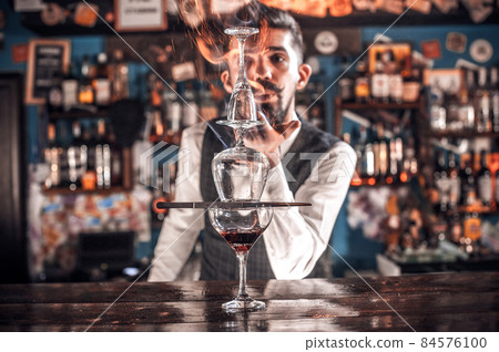 Young barman demonstrates his skills over the counter behind bar Young barman demonstrates his skills over the counter behind bar 84576100