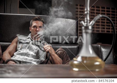 Sexy young man enjoy aromatic shisha in the hookah bar. Sexy young man enjoy aromatic shisha in the hookah bar. 84576104