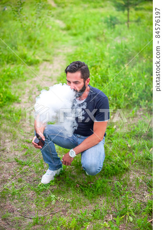 Modern smoker smoking an electronic smoke device. Vape. Modern smoker smoking an electronic smoke device. Vape. 84576197