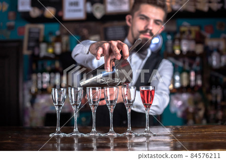 Young bartender demonstrates the process of making a cocktail at the night club Young bartender demonstrates the process of making a cocktail at the night club 84576211