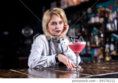 Young girl barman demonstrates his professional skills while standing near the bar counter in bar Young girl barman demonstrates his professional skills while standing near the bar counter in bar 84576212