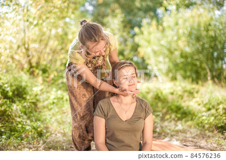 Massage professional demonstrates refreshing massaging methods on the grass. Massage professional demonstrates refreshing massaging methods on the grass. 84576236