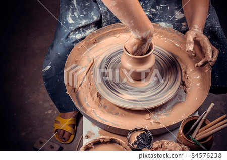 Creating vase of white clay close-up. The sculptor in the workshop makes a jug out of earthenware closeup. Twisted potter's wheel. Master crock. Creating vase of white clay close-up. The sculptor in the workshop makes a jug out of earthenware closeup. Twisted potter's wheel. Master crock. 84576238