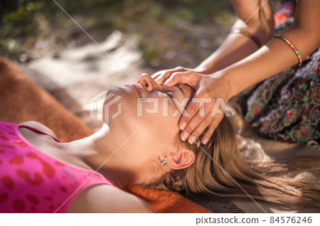 Woman masseuse applies her massage skills on her client on the grass. 84576246