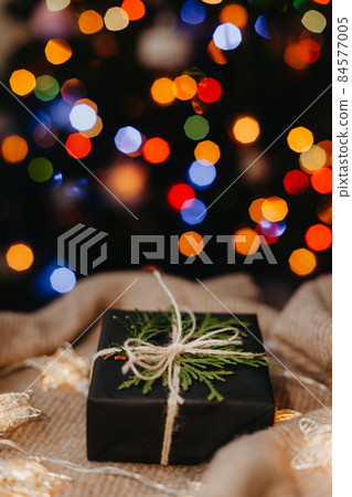 small gift laying on beige textile, decorated Christmas tree on background. small gift laying on beige textile, decorated Christmas tree on background. 84577005