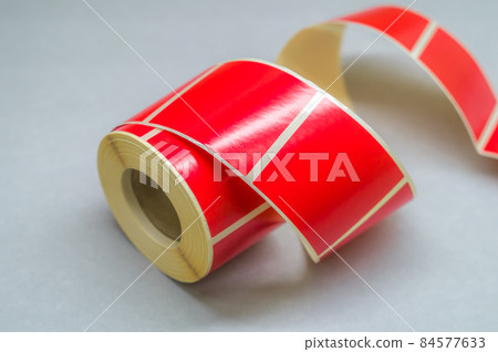 Roller tape red self-adhesive label. Material for printing and marking products. Thermal label. Selective focus, copy space Roller tape red self-adhesive label. Material for printing and marking products. Thermal label. Selective focus, copy space 84577633