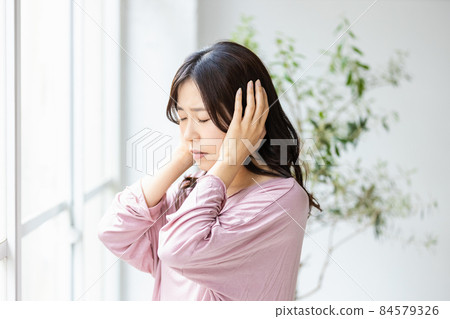 一個生病的女人站在客廳的窗戶旁,穿著家居服 一個生病的女人站在客廳的窗戶旁,穿著家居服 84579326