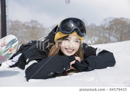 A young woman lying on the slopes, a snowboard girl A young woman lying on the slopes, a snowboard girl 84579435