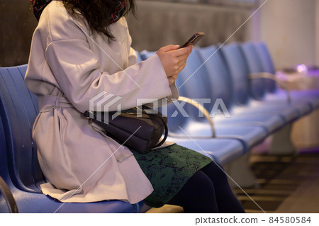A woman looking at a mobile phone at a bus stop A woman looking at a mobile phone at a bus stop 84580584
