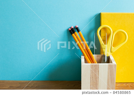 Yellow notebook, pencil holder, scissor, ruler on wooden desk. blue wall background. workspace Yellow notebook, pencil holder, scissor, ruler on wooden desk. blue wall background. workspace 84580865