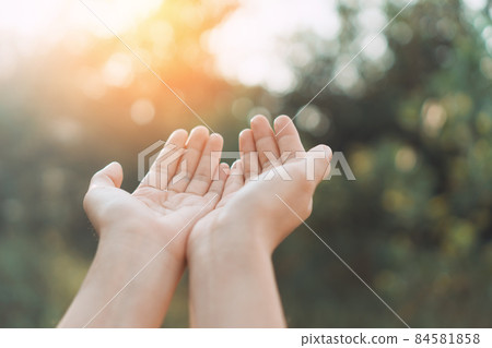 Woman open hand up to sunset sky and green blur leaf bokeh sun light abstract background. Woman open hand up to sunset sky and green blur leaf bokeh sun light abstract background. 84581858