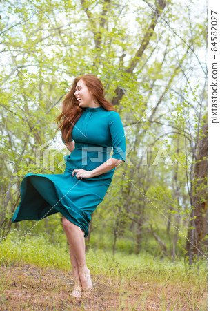Beautiful young woman posing in forest on blurred green background. Beautiful young woman posing in forest on blurred green background. 84582027