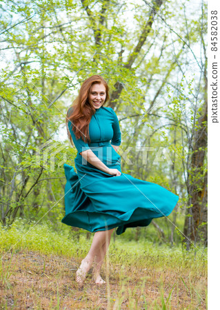 Beautiful young woman dance in forest on blurred green background. 84582038