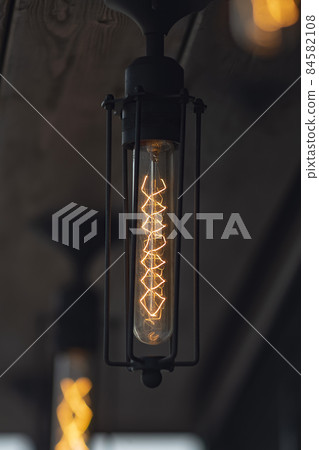 Long retro lamp with orange filament in a black body. 84582108