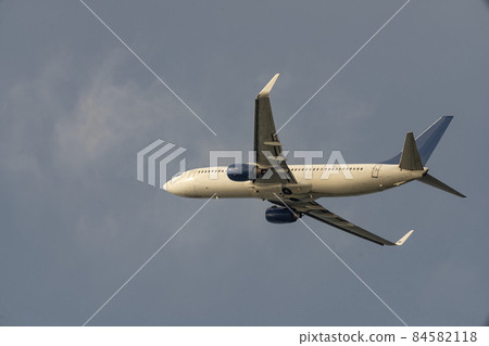Passenger twin engine plane against the backdrop of a cloudy sky. 84582118