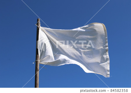 The white flag against the blue sky. Surrender concept. The white flag against the blue sky. Surrender concept. 84582358