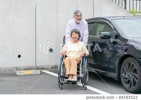 Senior couple wheelchair parking lot Senior couple wheelchair parking lot 84583522