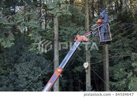 A young man riding a crane car gondola with a chainsaw 84584647