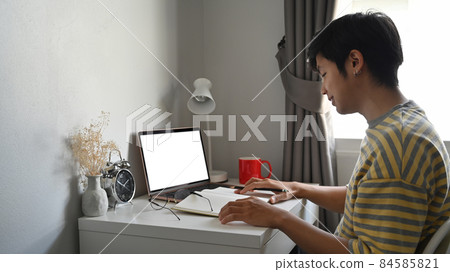 Side view asian man sitting in comfortable home and using laptop computer. 84585821