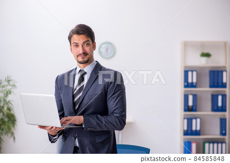Young male employee sitting at workplace Young male employee sitting at workplace 84585848