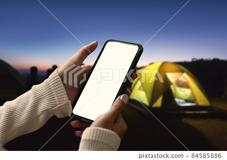 Young woman using smart phone near camping tent in the evening. Young woman using smart phone near camping tent in the evening. 84585886