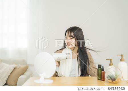 A woman using a hair dryer A woman using a hair dryer 84585980