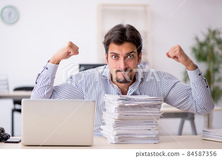 Young male employee and too much work in the office Young male employee and too much work in the office 84587356