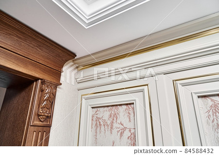 Wooden doorway and vintage wall panel with golden molding in light room Wooden doorway and vintage wall panel with golden molding in light room 84588432