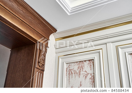 Wooden doorway and vintage wall panel with golden molding in light room 84588434