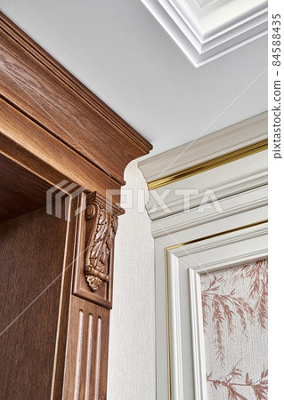 Wooden doorway and vintage wall panel with golden molding in light room Wooden doorway and vintage wall panel with golden molding in light room 84588435