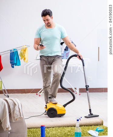 Young man husband doing vacuuming at home Young man husband doing vacuuming at home 84590883