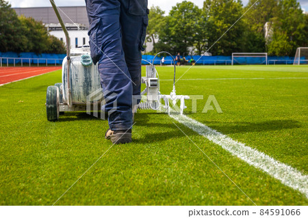 drawing of a white line on the green lawn of a football stadium 84591066