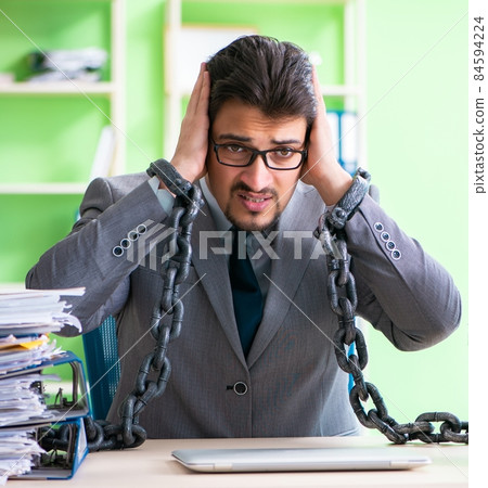 Employee chained to his desk due to workload Employee chained to his desk due to workload 84594224