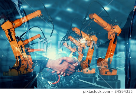Mechanized industry robot arm and business handshake double exposure Mechanized industry robot arm and business handshake double exposure 84594335