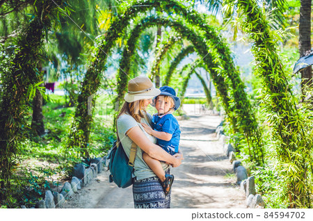 Mother and son in a tropical garden Mother and son in a tropical garden 84594702