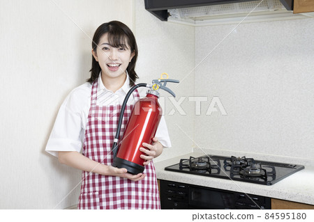 Woman with a fire extinguisher in the kitchen 84595180