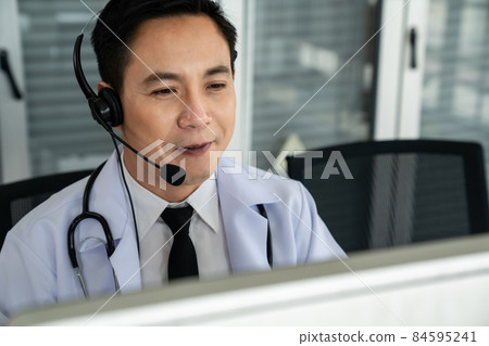 Doctor wearing headset talking actively on video call in a clinic or hospital . Doctor wearing headset talking actively on video call in a clinic or hospital . 84595241