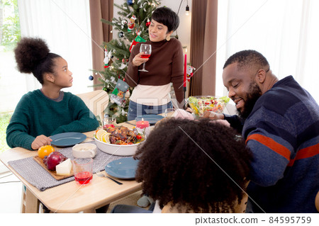 Happy African family eating food in dinner on festive thanksgiving eve day together at home.