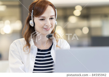 A foreign woman wearing a headset that speaks to a computer 84595942