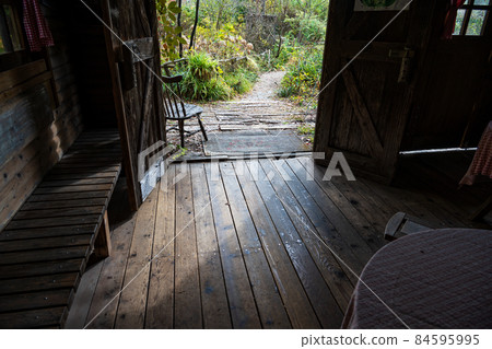 An old wooden chair sits in the doorway leading to a poorly maintained, pristine garden. An old wooden chair sits in the doorway leading to a poorly maintained, pristine garden. 84595995