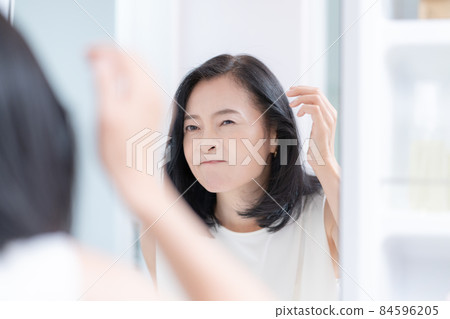 中年婦女一邊照鏡子一邊檢查頭髮 84596205