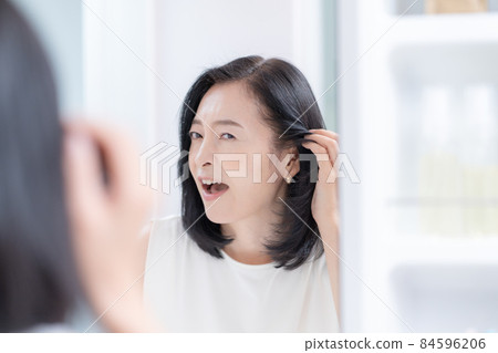 中年婦女一邊照鏡子一邊檢查頭髮 84596206