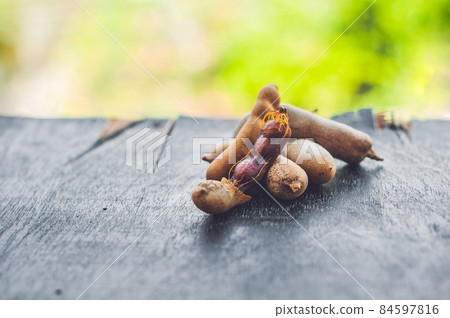 Sweet ripe tamarind pods on old wood background Sweet ripe tamarind pods on old wood background 84597816